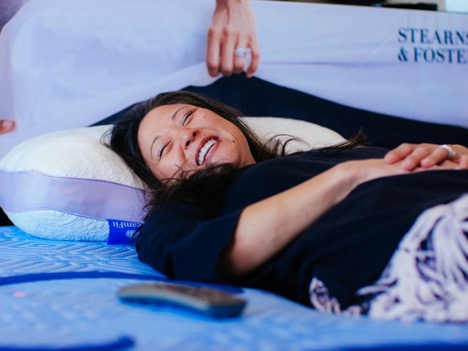 woman smiling laying on mattress
